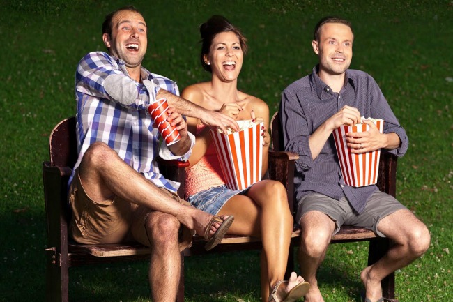 three friends watching a movie at cinema outdoors; Shutterstock ID 233995180